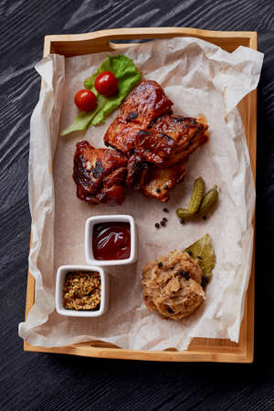 Ribs cooked on the grill with sauerkraut. On parchment paper, decorated with cucumbers and cherry tomatoesの写真素材