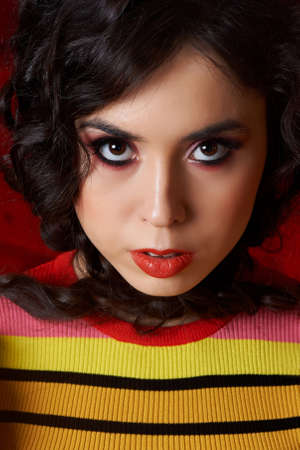 Studio fashion shooting. The girl in a bright outfit, top and pants flared in red and orange colors....