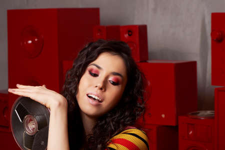 Studio fashion shooting.The girl in a bright outfit, top and pants flared in red and orange tones....