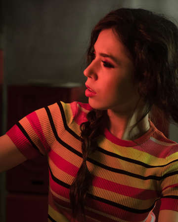 Studio fashion shooting. The girl in a bright outfit, top and pants flared in red and orange colors....