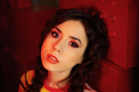 Studio fashion shooting. The girl in a bright outfit, top and pants flared in red and orange colors....
