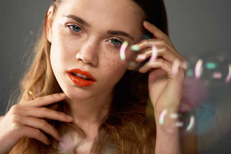 Portrait of young beautiful girl in Studio, with professional makeup. Beauty shooting. The beauty of soap bubbles. The rainbow flaresの写真素材