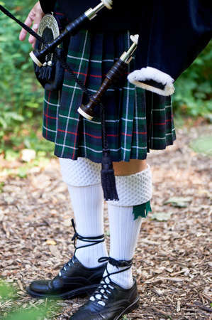 White socks.A man with a bagpipe, a kilt in a cage with a green and red stripe.Culture. The details of the skirt of the kilt and the little bags with tassels. Closelyの写真素材