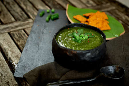 Green broccoli soup, on a gray stand, and a wooden background. Rustic style. Simple, nutritious...