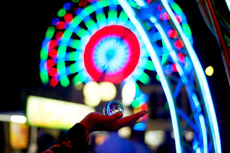 Ferris wheel through a glass ball on the palm of your hand. The atmosphere of celebration and rest....
