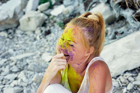 The festival of Holi. The joy and happiness. Paint on the face. Blonde girl