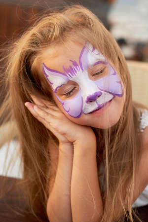 Pretty exciting blue-eyed girl of 5 years with a pink face painting