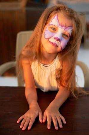 Pretty exciting blue-eyed girl of 5 years with a pink face painting