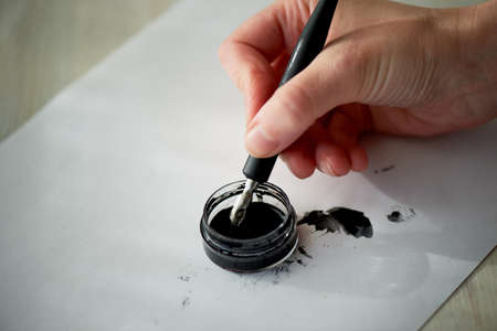 A womans hand writes with ink, a fountain pen. Writing. The creative process of creating a workの写真素材