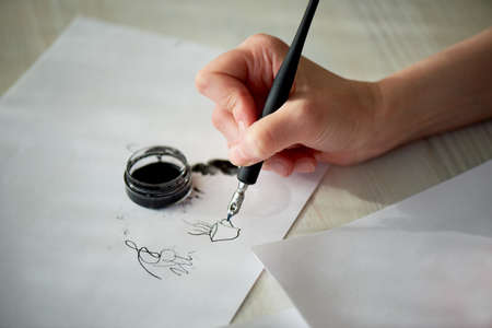 A womans hand writes with ink, a fountain pen. Writing. The creative process of creating a workの写真素材