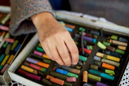 Box with pastel crayons and artists hands. Drawing with dry pastel
