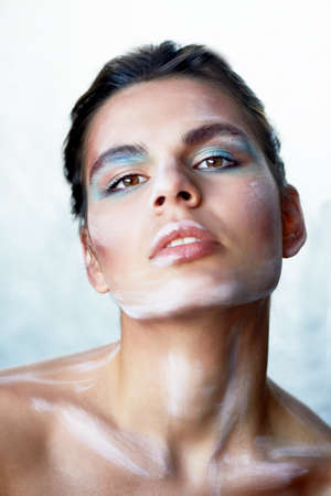 Creative person. Makeup with paint strokes. Throws his head back. The background is silver.の写真素材