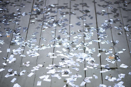 Silver confetti scattered on a white wooden floor. New year party.