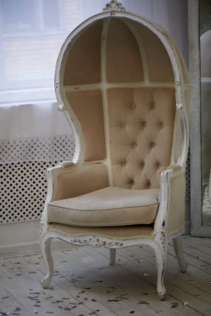 Massive old chair with light fabric upholstery and high closed back.