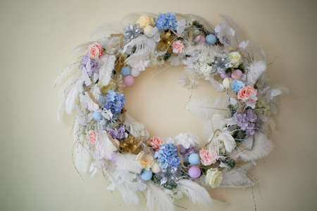Decoration for the interior. Wreath of blue and white scale of feathers and flowers on a light wall background.の写真素材