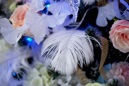 Decorating the Christmas tree with feathers and flowers and glowing garlands. Closely