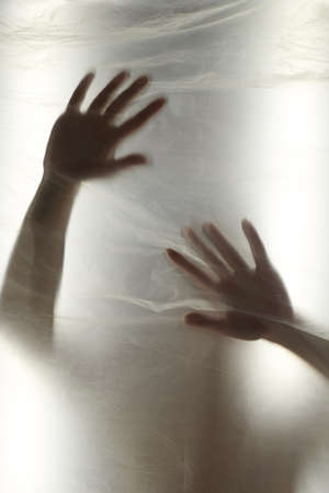 Hands through the clear film.Beautiful delicate feminine hands. A symbol of illusiveness and...