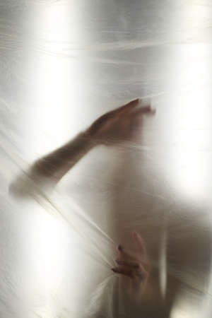 Hands through the clear film.Beautiful delicate feminine hands. A symbol of illusiveness and...