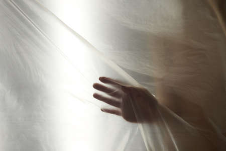 Hands through the clear film.Beautiful delicate feminine hands. A symbol of illusiveness and unreality.の写真素材