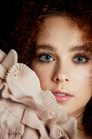 A girl with lush curly red hair. Delicate makeup with false eyelashes in doll style.Ruches cream color.の写真素材