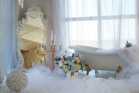 Bath on lions Golden paws. The atmosphere of romance and love. Light interior, chiffon, flowers.