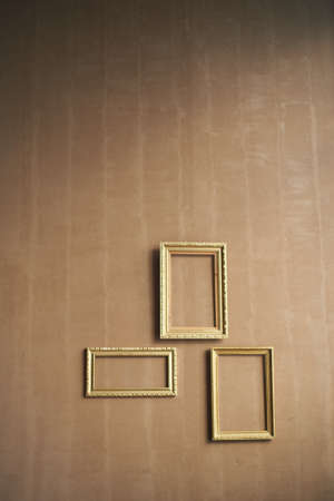 Minimalism. Brown wall with empty gold frames.