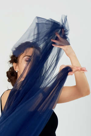 A slender gymnast in black tights dances with a blue chiffon that develops. Aesthetics of danceの写真素材