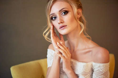 Portrait of a beautiful miniature bride in a lace dress. Hair with curls. Emphasis in make-up on the...