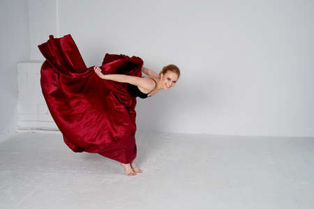 A gymnast in a dark top and a red silk skirt. The color of passion, of aggression. Tango. Plastic...