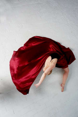 A gymnast in a dark top and a red silk skirt. The color of passion, of aggression. Tango. Plastic body, airiness , weightlessness and lightness.の写真素材