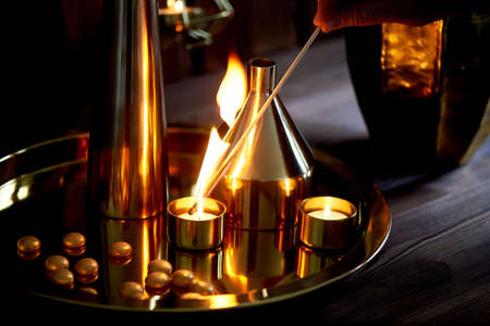 Hand lights a candle with a long match with a bright flame.The warm Golden gamma. Evening comfort....