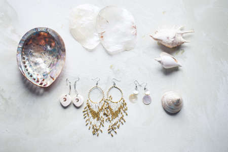 Sea collection on grey marble background.Seashell and mother-of-pearl earrings. Summer jewelry.の写真素材