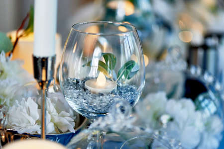 Led candles burning inside a transparent glass goblet. Blue gamma in the design.