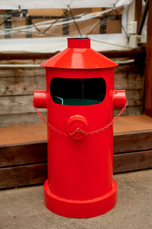 The garbage container is metallic red in a loft-style space on the street.