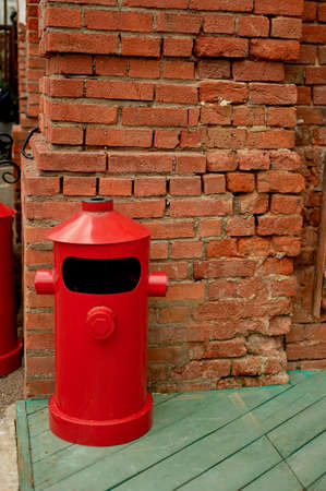 The garbage container is metallic red in a loft-style space on the street.