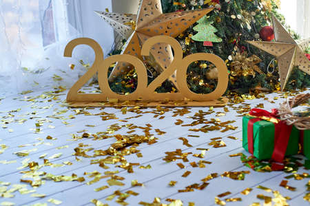 Meeting the new year 2020. Gold numbers on the background of the Christmas tree. Confetti on the...