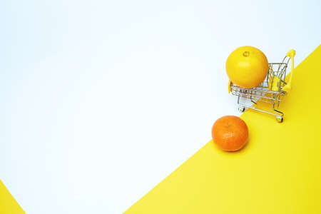 Grocery basket on wheels, minimalism. On light background. Online shopping. Grocery basket on wheels, minimalism. On light background. Online shopping. Citrus for health.の写真素材