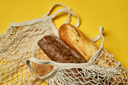 Replacing plastic bags. Taking care of the environment.Grid with bread on a yellow background. Minimalism.の写真素材