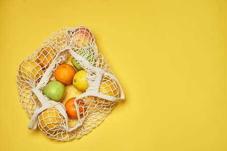 Replacing plastic bags. Taking care of the environment.Grid with fruit on colored paper, fortification. Minimalism.の写真素材