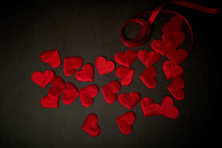 Valentines day, a Declaration of love.A lot of red hearts on a dark gray background, and a red ribbon.の写真素材