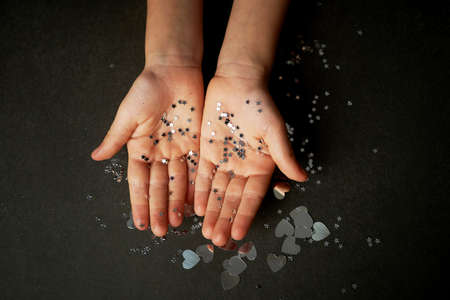 Childrens hands in glitter sours of silver color. Faith in miracles.の写真素材