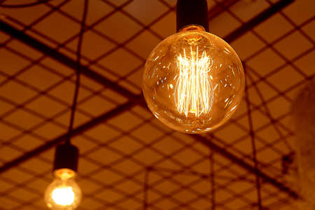 Ancient Edison lamps on black wires. Warm light in the design of the cafe.