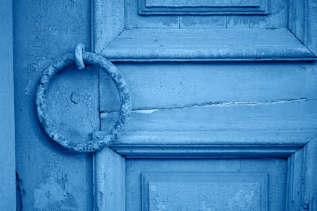 Old vintage door with peeling paint and a rusty handle in the form of a ring, Classic blue. The 2020 trend.の写真素材
