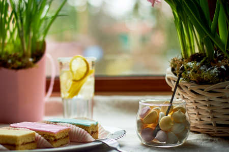 Breakfast on a bright day. Flowers, sweets, and lemonade. Warm light.