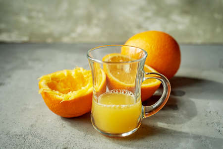 Orange juice in a glass, next to the crusts of a squeezed orange. Simple and raw food.