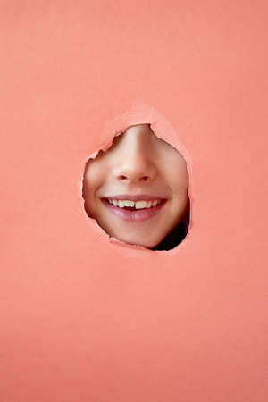 Taking care of childrens teeth, regular checkups at the dentist. Change of milk teeth. Trend-a face in a hole in the paper.の写真素材