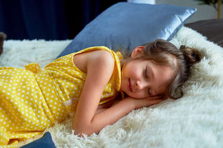 A 6-year-old girl in a yellow dress. I fell asleep with my clothes on. Fatigue from playing and brain activity. I was starved.の写真素材
