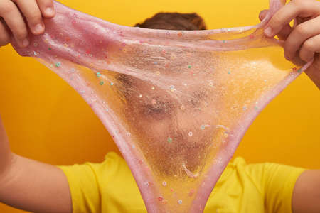 Boy, 9 years old. Blue eyes, short hair. Holds the slime near his face. Children's game.