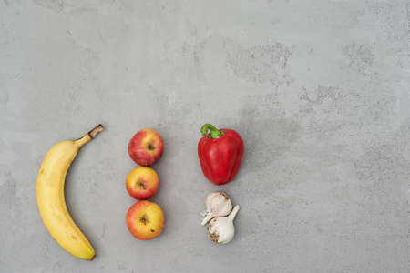 Natural, natural looking fruits and vegetables, on a grey concrete background. Banana, Apple, pepper...