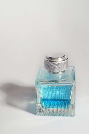 Perfume in a transparent bottle, light blue on a white background. Aromatherapy, perfume production....